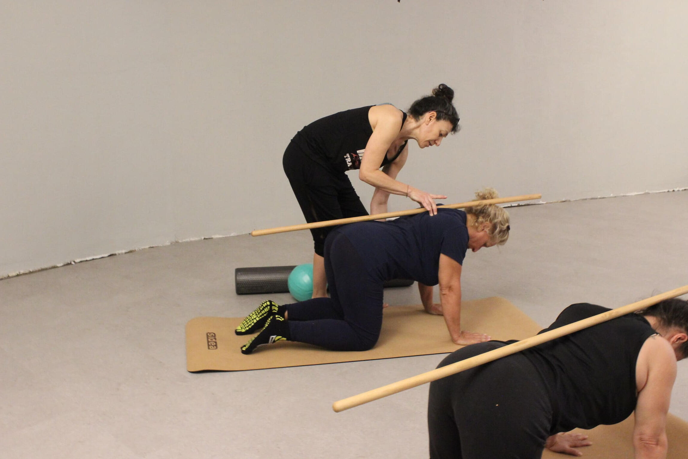 insegnante-pilates-bolzano-qualificata insegnante di pilates che corregge allieva esercizio con bastone